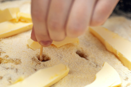 raw apple pie being prepared, showcasing the process of poking holes in the crust with a wooden...