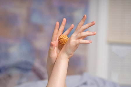 Elegant female hands perform self-massage with a hand-carved juniper wood ball for natural relaxation and therapeutic reliefの写真素材