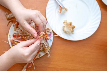 Elegant female hands carefully pick crab meat from shells for a delicious seafood meal, showcasing gourmet food preparationの写真素材