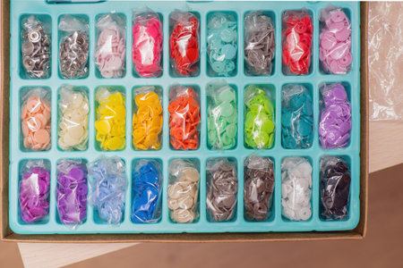 Assorted colorful plastic snap fasteners neatly arranged in rows within plastic bags, showcasing...
