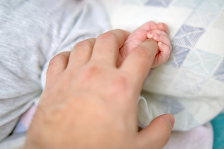 newborns tiny hand gripping fathers index finger, capturing a heartwarming moment of early bonding and trustの写真素材