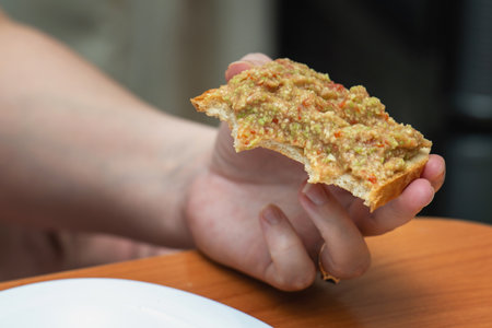 woman's hand holds a half-eaten toast, capturing a casual and delicious snack moment.の写真素材