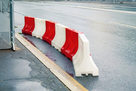White and red plastic barriers marking pedestrian boundaries during road construction, ensuring safety and traffic control.の写真素材