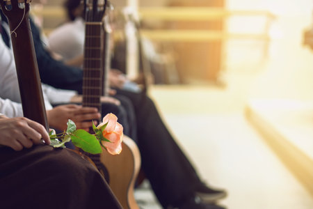 Guitar competition contestants holding instruments await results, with one holding a red rose in anticipationの写真素材