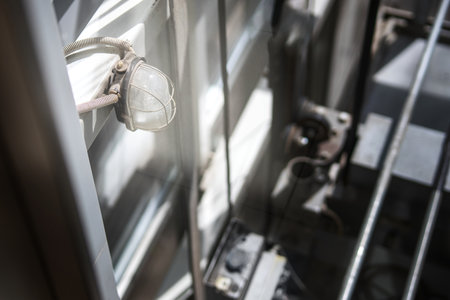 Protected light fixture with metal mesh casing in an elevator shaft, showcasing industrial safety...