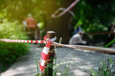 People ignoring safety rules by crossing the red-white barrier tape, demonstrating violation of established regulationsの写真素材