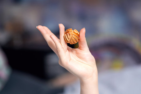 Elegant female hand holding a carved honeysuckle wood massage ball for therapeutic and relaxation purposesの写真素材