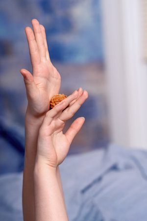 Elegant female hands holding a carved honeysuckle wood massage ball for therapeutic and relaxation purposes.の写真素材