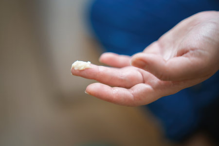 A small amount of white cream on a middle finger, showing skincare or product application.の写真素材