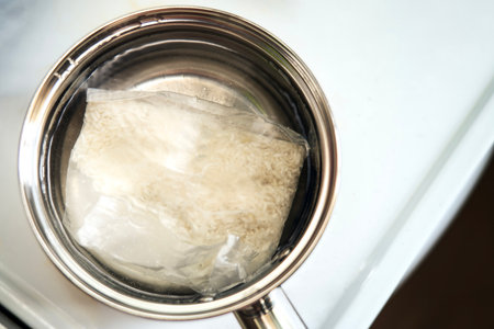 Rice pouch boiling in a small metal pot with water. Quick and convenient meal preparation concept.の写真素材