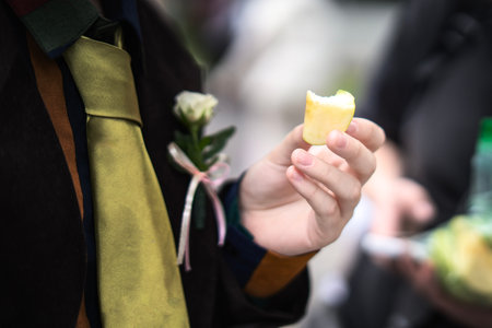 teen's hand holding a bitten apple slice during a snack break.