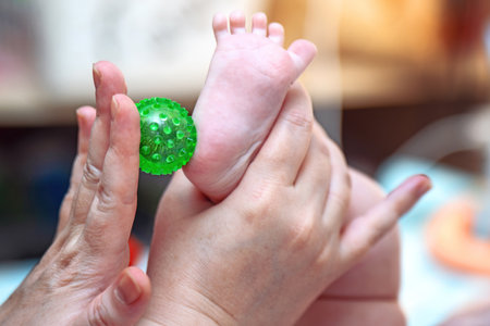 Infant foot massage for sensory activity using a green spiked plastic Su Jok ball.の写真素材