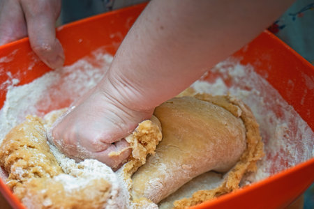 Hand kneading honey cookie dough orange plastic bowl. Homemade baking process.