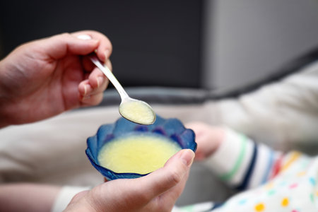 A teaspoon with baby vegetable puree during infant feeding time.の写真素材