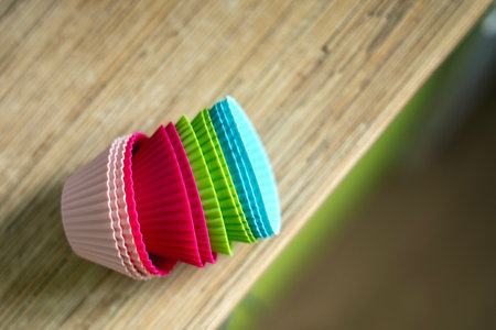 Colorful silicone round baking molds stacked on a table, ready for pastry preparation.の写真素材