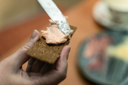 Spreading caviar and butter mixture on rye crispbread with table knife, perfect for culinary blogs and gourmet food content.の写真素材