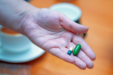 A mans hand holding two large vitamin and dietary supplement capsules for health.の写真素材