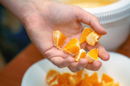 A teen's palm holding small chopped orange pieces for pie preparation, perfect for baking tutorials and cooking blogs.の写真素材