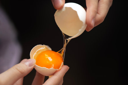 Teen's hands separating egg yolk from white eggshell