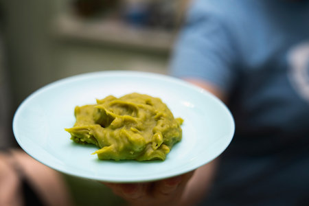 Woman holding blue ceramic bowl with homemade pea praline during lunch at home.の写真素材