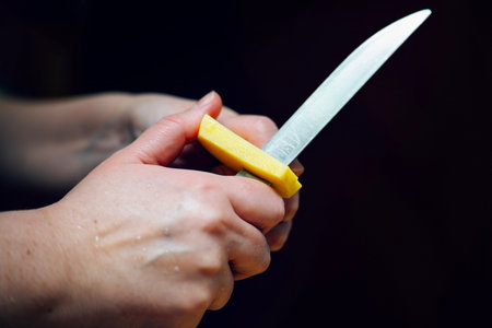 Cutting raw potato sticks with vintage knife on dark background.の写真素材