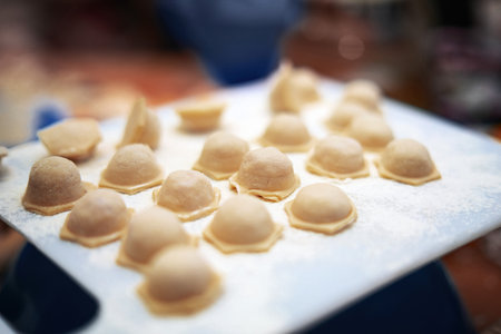 Homemade hexagonal dumplings on white plastic board before boiling in water.の写真素材