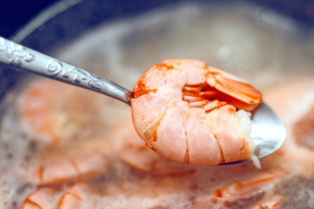 Large red langoustine on a metal spoon lifted from a pot of boiling water with shrimp. Seafood cooking process.の写真素材