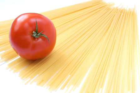 Tomato lying on raw spaghettiの写真素材