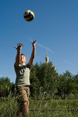 A little boy plays a ball with sky at background の写真素材
