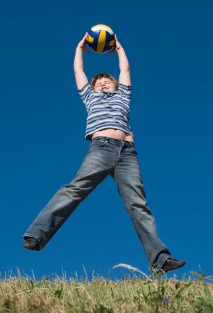 A little boy plays a ball with sky at backgroundの写真素材