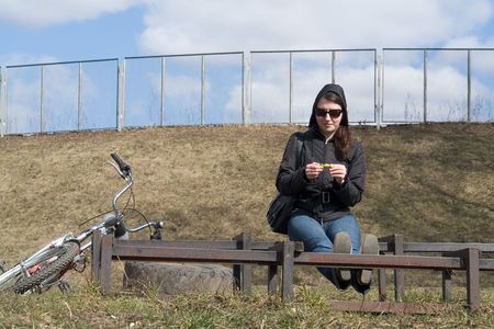 Spring. Woman rests on the bench after bicycle jaunt.の写真素材