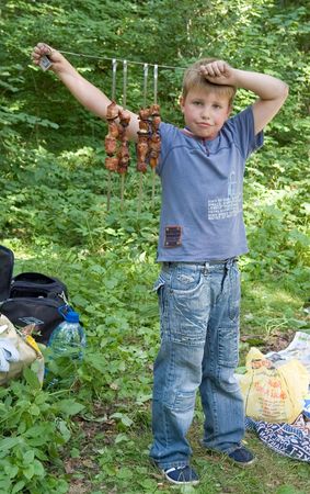 Boy shows freshly-fire shashlik on the spitの写真素材