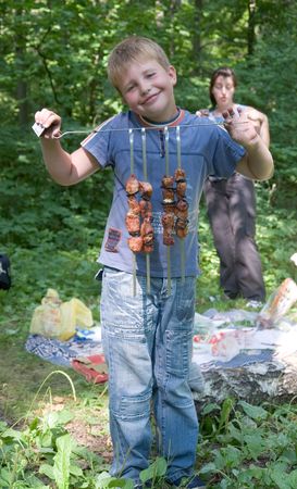 Boy shows freshly-fire shashlik on the spitの写真素材