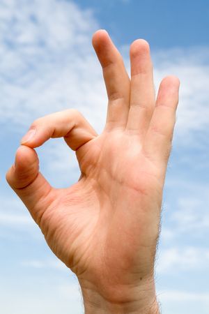 OK` hand gesture with blue sky at backgroundの写真素材