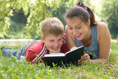 Mum and the son reads the book on a lawn in parkの写真素材