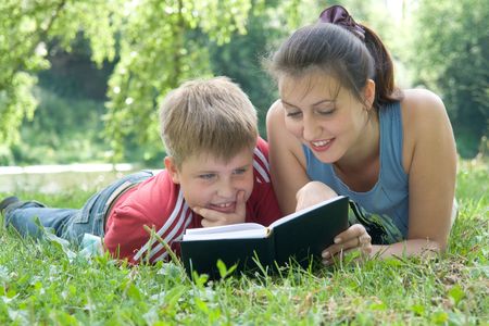 Mum and the son reads the book on a lawn in parkの写真素材