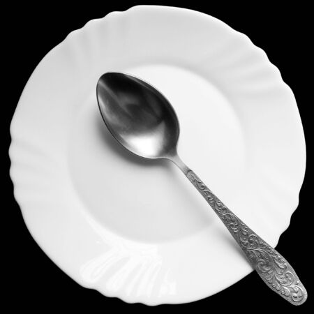 spoon on a white plate on a black backgroundの写真素材