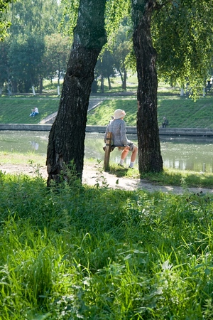 old woman has a rest in park near the riverの写真素材