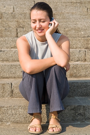 girl with mobile phone on a stone staircaseの写真素材