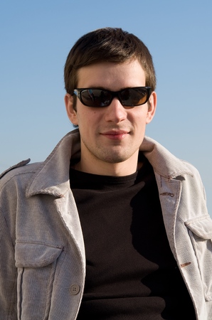 beautiful young man in black glasses against the skyの写真素材