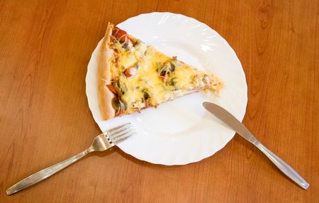 Pizza piece on a white plate with plug and knifeの写真素材