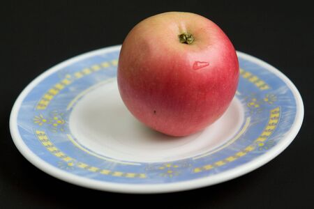 Red apple on a saucer with a blue borderの写真素材