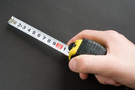 Hand with a measuring tape on a black background