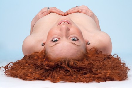 Attractive red-haired woman lies on a blue backgroundの写真素材