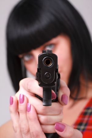 Aiming. Young woman with a gun close up.