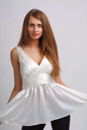 beautiful young woman in short dress standing against gray backgroundの写真素材