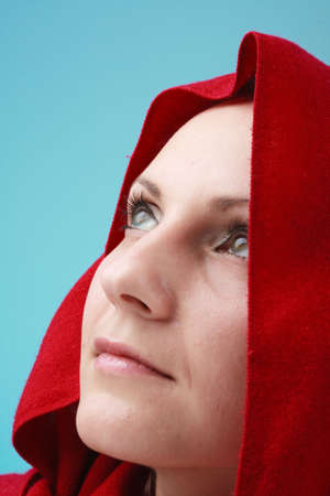 Young woman in red hood on a blue background