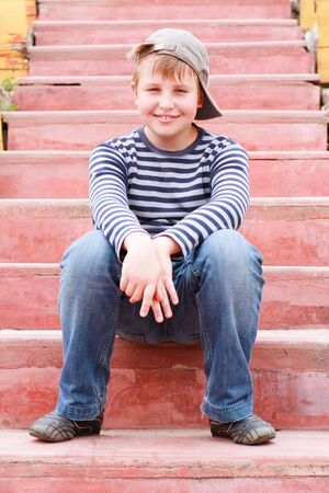 joyful little boy sitting on stairs in the parkの写真素材