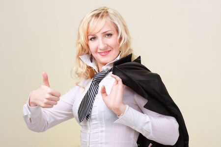 Smiling business woman with thumbs up standing against yellow backgroundの写真素材