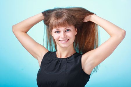 Smiling young lady with beautiful hair on a blue backgroundの写真素材